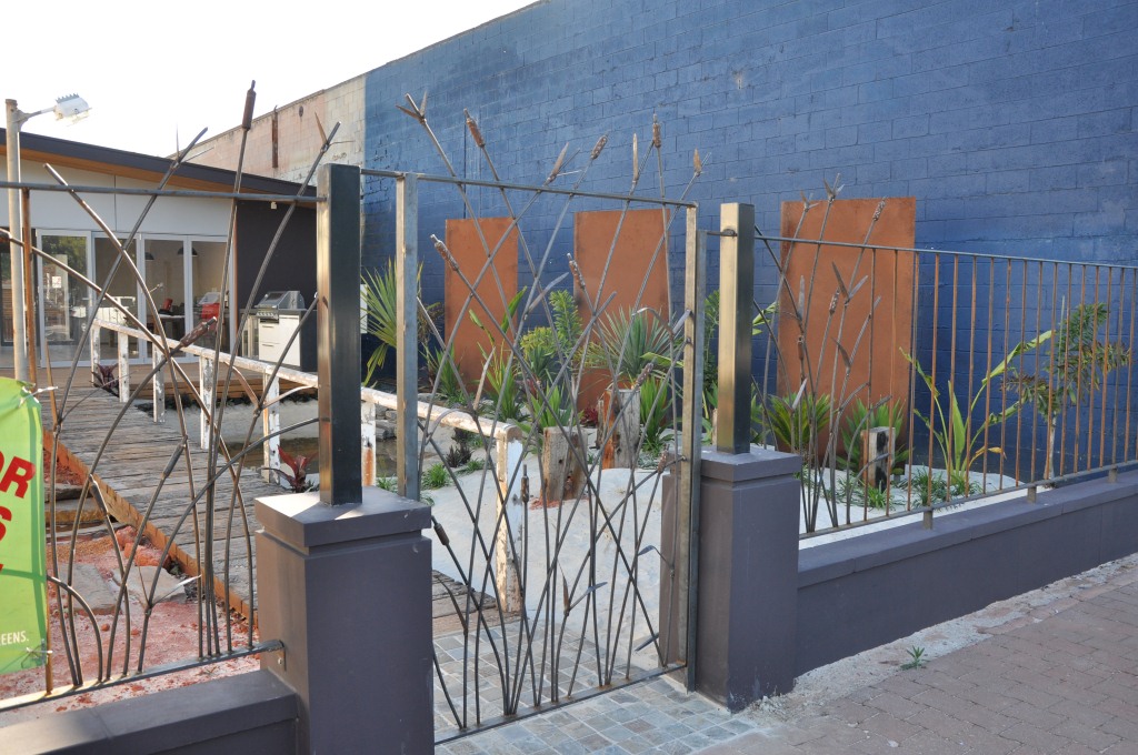 The organic forms of a wrought iron bull rush fence and steel gate add a contemporary touch to this garden design centre in Adelaide.